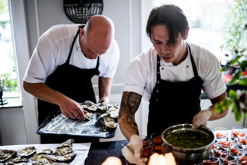Two professional chefs preparing fresh ingredients in a bright restaurant kitchen