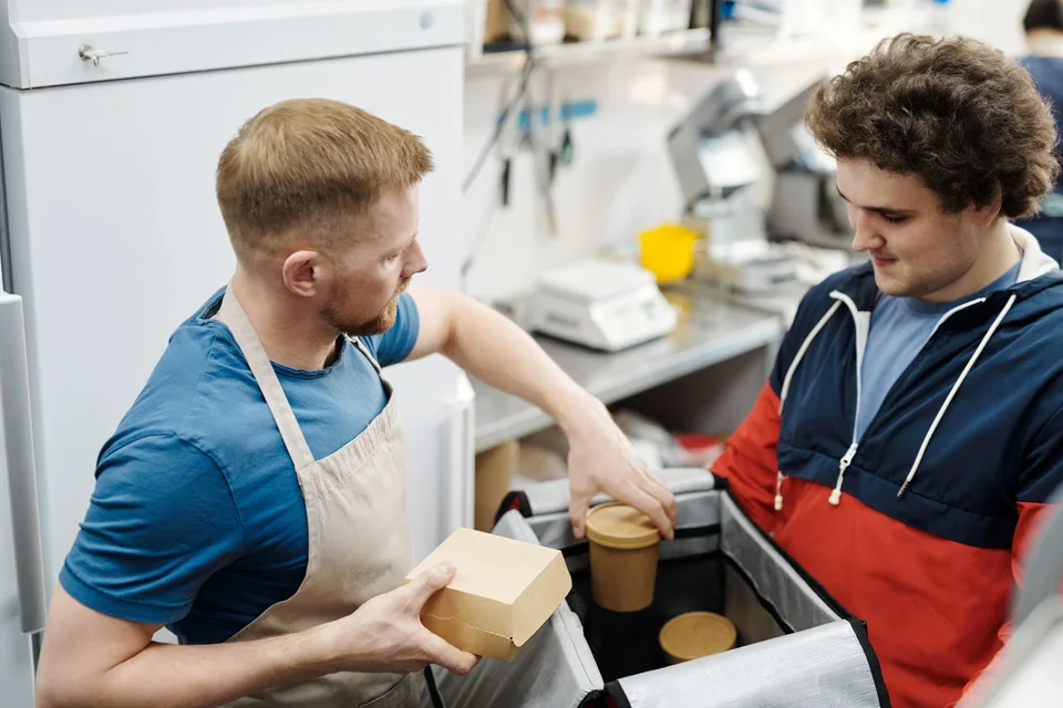 Takeaway kitchen worker packing an order for a delivery courier